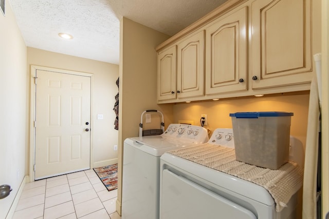 laundry area featuring light tile patterned floors, cabinet space, a textured ceiling, separate washer and dryer, and baseboards