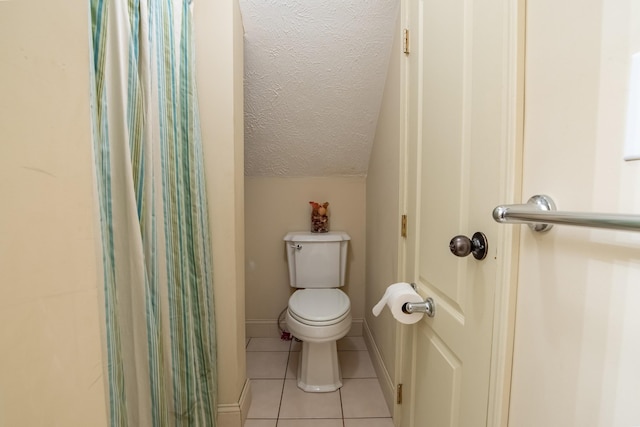 bathroom with a textured ceiling, lofted ceiling, tile patterned flooring, toilet, and baseboards