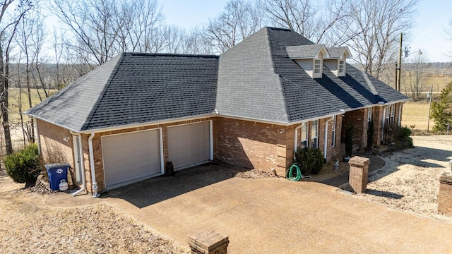 view of side of home featuring a garage, driveway, brick siding, and a shingled roof