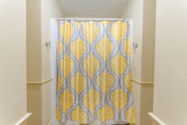 full bath with a textured ceiling and a shower with shower curtain