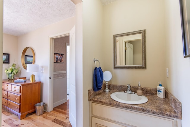 bathroom with vanity, a textured ceiling, and wood finished floors