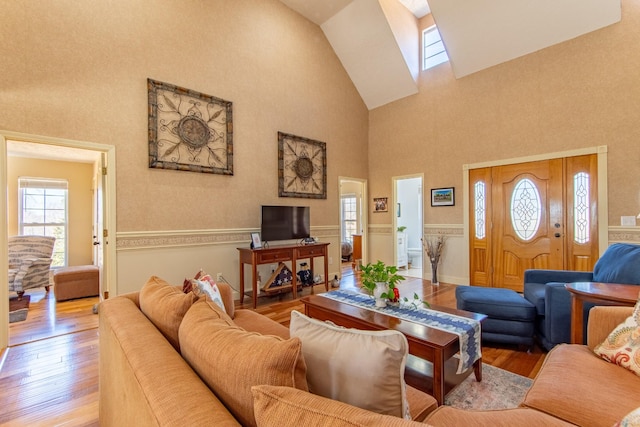 living area with hardwood / wood-style flooring, high vaulted ceiling, and a wainscoted wall