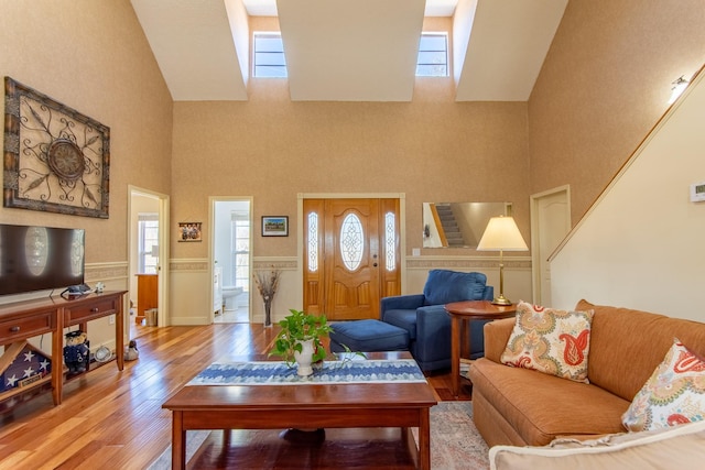 living area with a wainscoted wall, a high ceiling, and wood finished floors