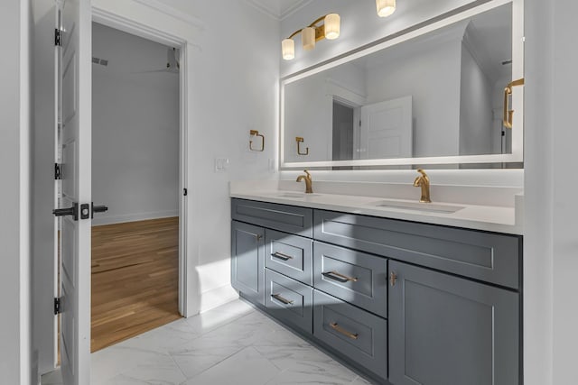 bathroom with marble finish floor, a sink, baseboards, and double vanity