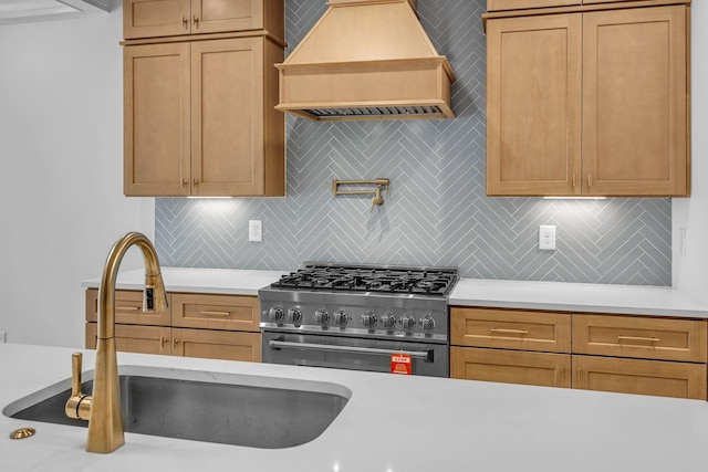 kitchen featuring light countertops, custom range hood, a sink, and high end stainless steel range