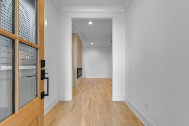 hall featuring light wood-style floors, baseboards, and crown molding