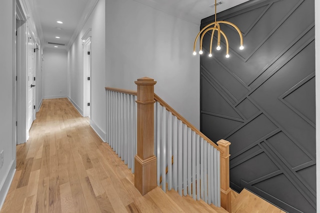 corridor featuring recessed lighting, a decorative wall, an upstairs landing, baseboards, and light wood finished floors