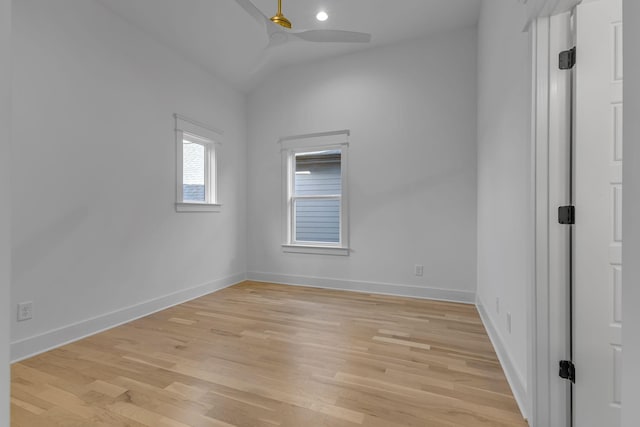 spare room with light wood-style floors, vaulted ceiling, baseboards, and a ceiling fan