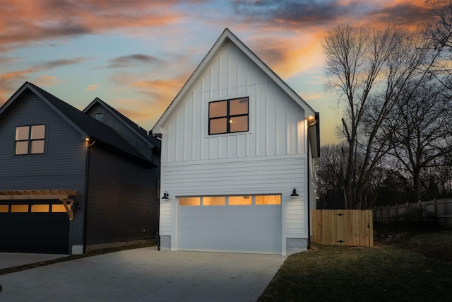 view of front of property featuring a garage, concrete driveway, board and batten siding, and fence