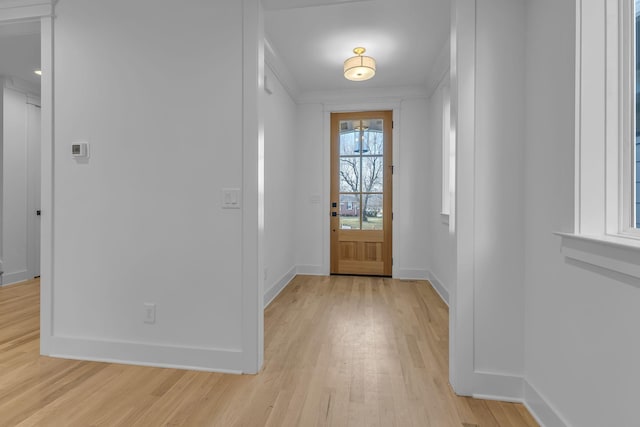 entryway with light wood-style flooring, baseboards, and crown molding