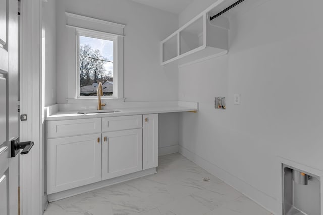 clothes washing area featuring marble finish floor, cabinet space, a sink, and baseboards