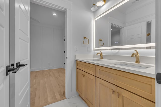 full bathroom featuring double vanity, a decorative wall, and a sink