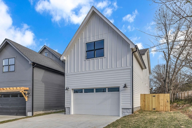 modern farmhouse with board and batten siding, concrete driveway, fence, and a garage