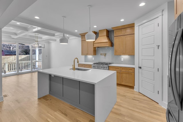 kitchen featuring custom exhaust hood, light wood-style flooring, a sink, range, and black fridge