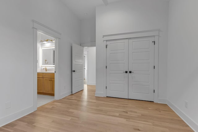 unfurnished bedroom featuring baseboards, a closet, connected bathroom, and light wood-style floors