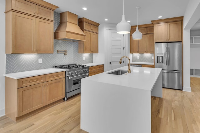 kitchen featuring light wood finished floors, premium range hood, a sink, and appliances with stainless steel finishes