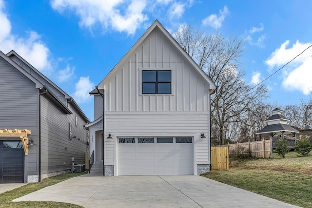 modern farmhouse style home with central air condition unit, a garage, fence, a front lawn, and board and batten siding