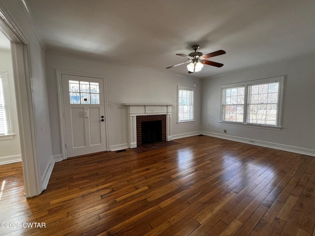 unfurnished living room with a brick fireplace, crown molding, baseboards, and hardwood / wood-style flooring