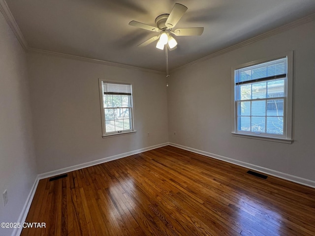 empty room with dark wood-style floors, crown molding, visible vents, ceiling fan, and baseboards