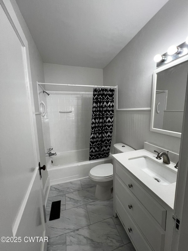 full bathroom featuring toilet, a wainscoted wall, vanity, marble finish floor, and shower / bath combination with curtain