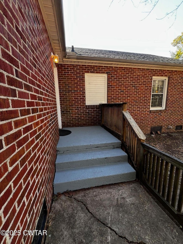 exterior space with roof with shingles and brick siding