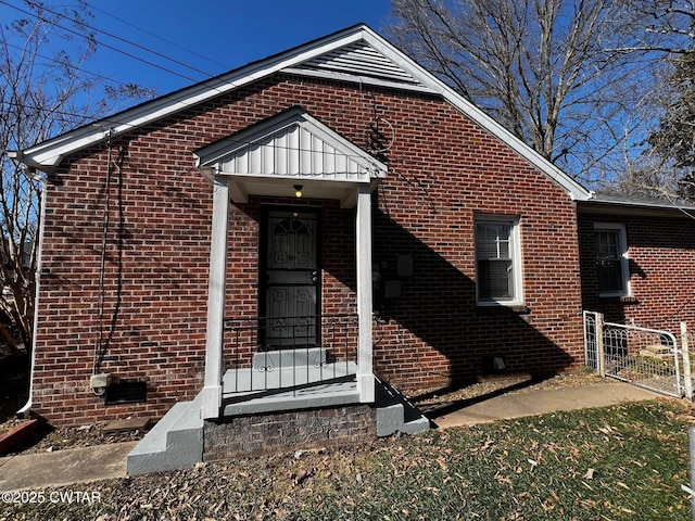 view of front of home featuring crawl space, brick siding, and a gate