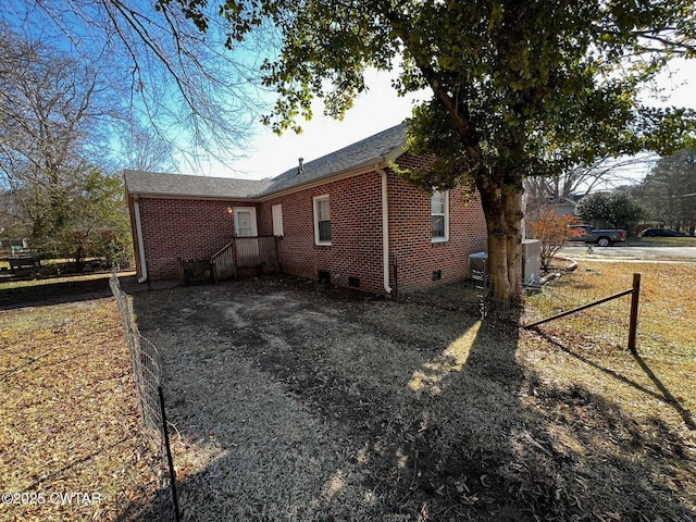 view of side of property with crawl space, brick siding, fence, and central air condition unit