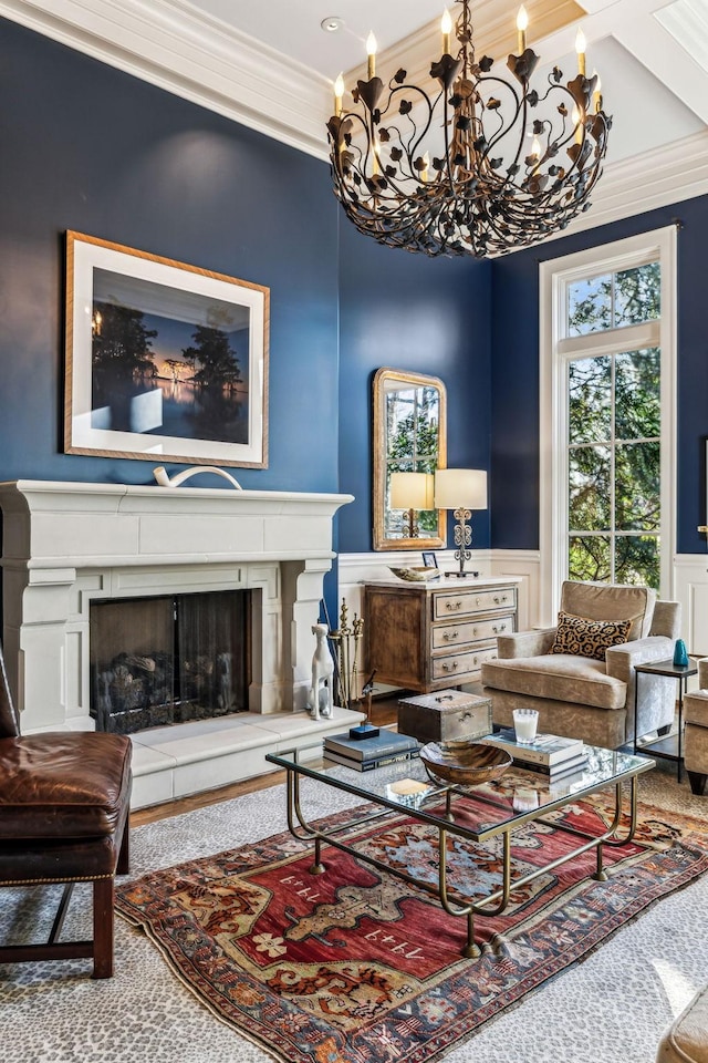 living area with a fireplace with raised hearth, crown molding, and wainscoting