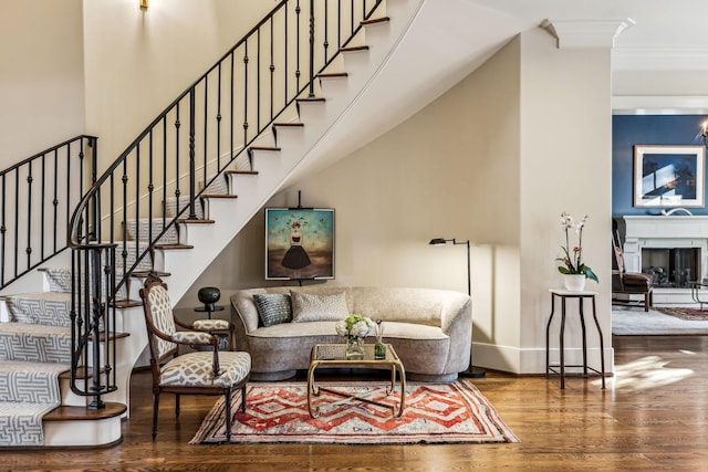 living room with baseboards, a towering ceiling, stairway, wood finished floors, and a fireplace