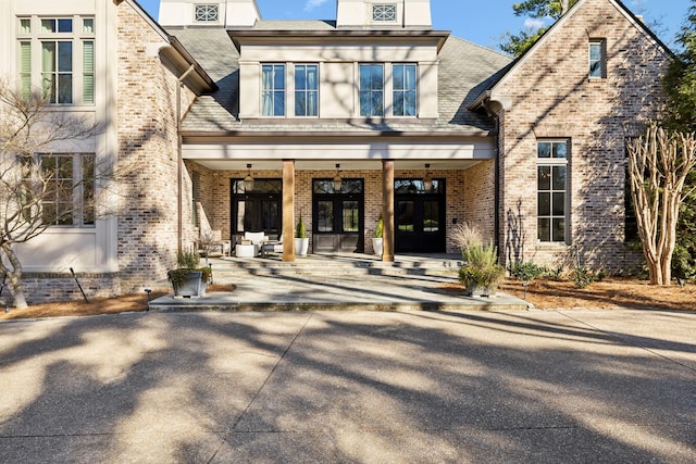 doorway to property with brick siding, covered porch, and french doors