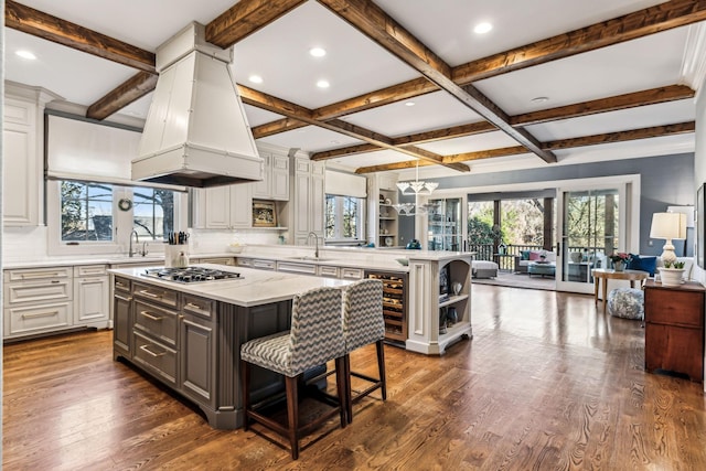 kitchen featuring open floor plan, a peninsula, dark wood-style flooring, and island exhaust hood