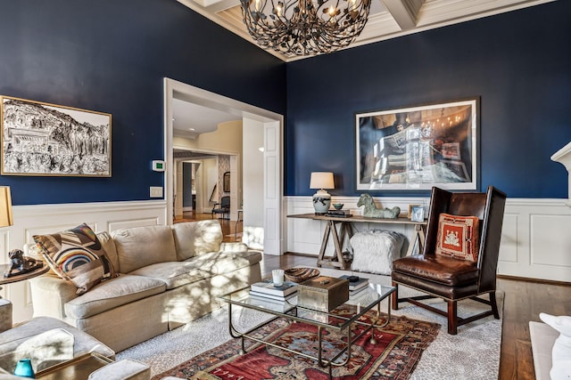 living area with beam ceiling, a wainscoted wall, a notable chandelier, and wood finished floors