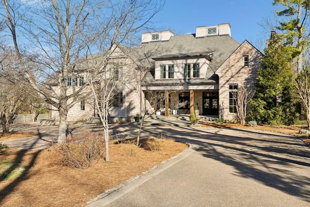 view of front of property with brick siding, driveway, and roof with shingles