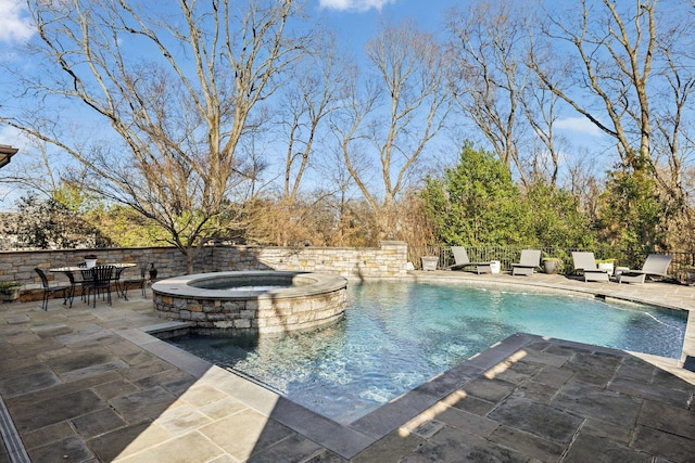 view of pool with a pool with connected hot tub, fence, and a patio