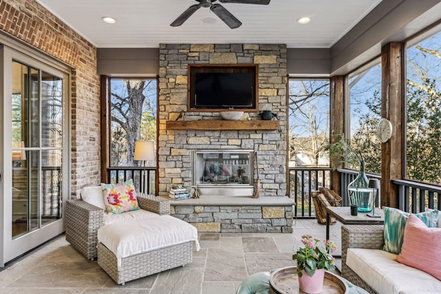 sunroom / solarium with an outdoor stone fireplace and ceiling fan