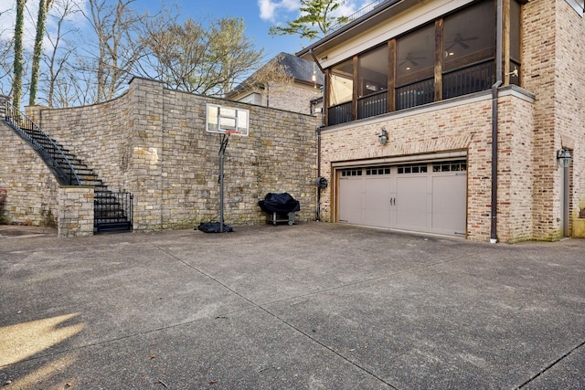 view of side of property featuring a garage, a sunroom, concrete driveway, and brick siding