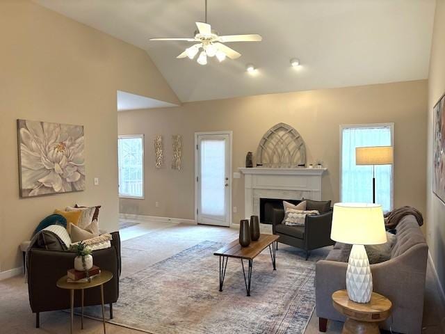 carpeted living room with baseboards, a fireplace, high vaulted ceiling, and ceiling fan