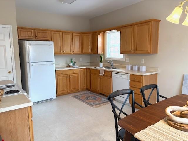 kitchen featuring white appliances, light countertops, a sink, and light floors