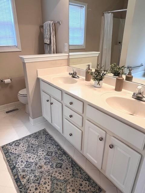 bathroom featuring double vanity, visible vents, toilet, and a sink