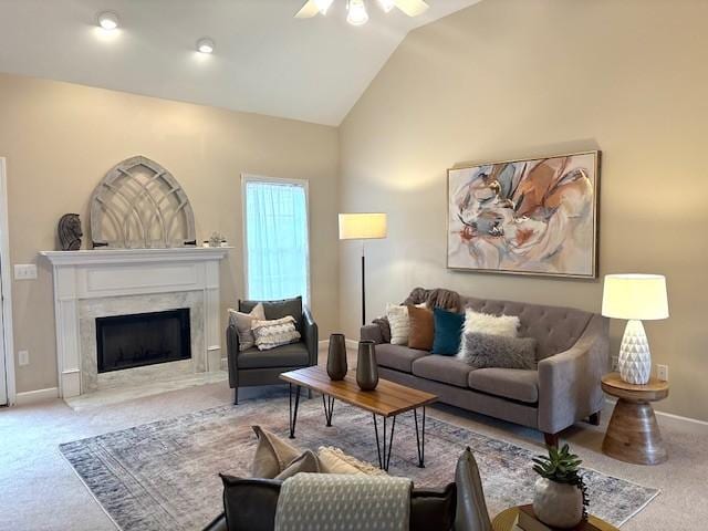 carpeted living area featuring a premium fireplace, baseboards, a ceiling fan, and vaulted ceiling