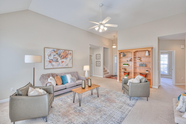 living area featuring light carpet, a ceiling fan, lofted ceiling, and stairs