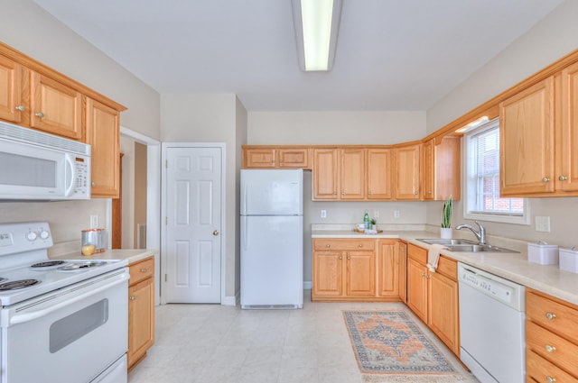 kitchen featuring white appliances, light countertops, light brown cabinets, and a sink