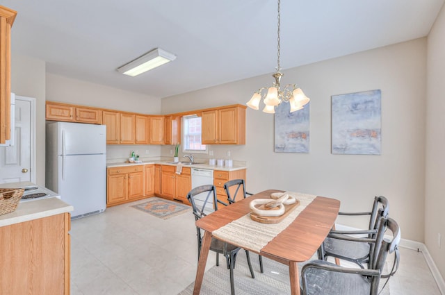 kitchen featuring white appliances, light brown cabinetry, a sink, light countertops, and a chandelier