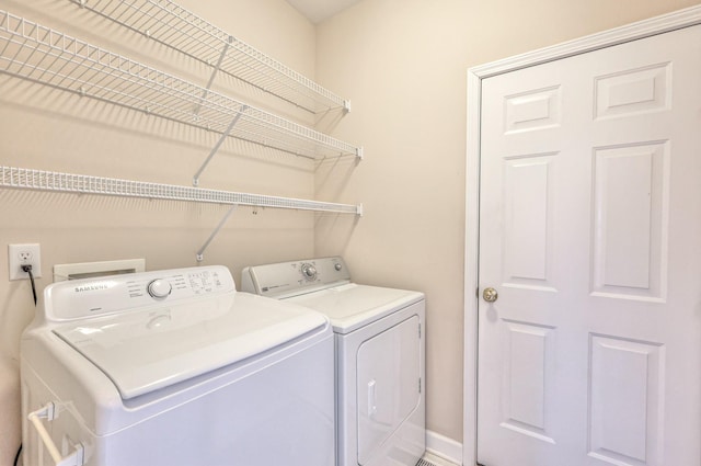 clothes washing area featuring separate washer and dryer and laundry area