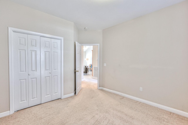 unfurnished bedroom featuring visible vents, baseboards, a closet, and light carpet