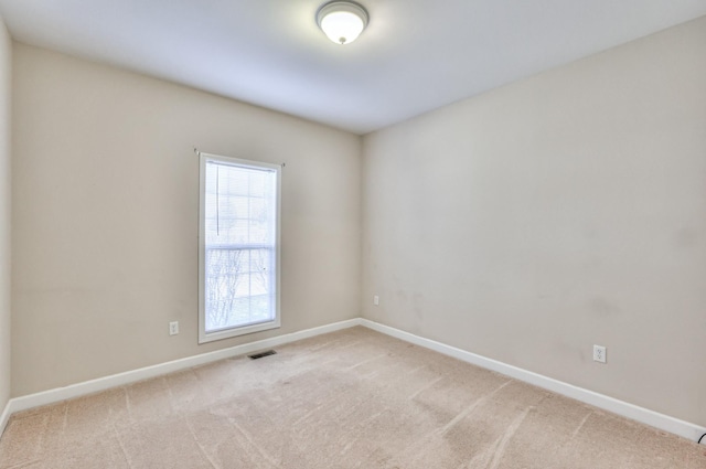 empty room with visible vents, baseboards, and light colored carpet