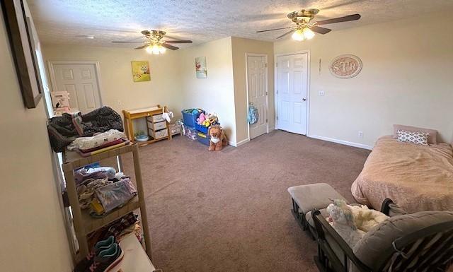 rec room featuring baseboards, a ceiling fan, dark colored carpet, and a textured ceiling