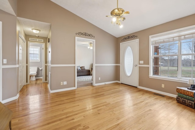 foyer with light wood-type flooring, visible vents, baseboards, and vaulted ceiling