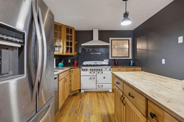 kitchen with light wood finished floors, stainless steel fridge with ice dispenser, butcher block counters, wall chimney exhaust hood, and double oven range