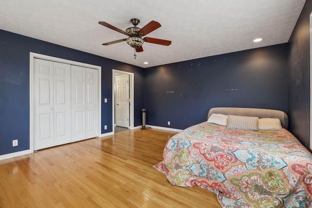 unfurnished bedroom with a closet, wood finished floors, a ceiling fan, and baseboards